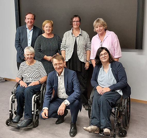 Gruppenfoto: Karl Lauterbach ist zwischen den beiden Rollstuhlfahrerinnen Anieke Fimmen und Sigrid Arnade in der Hocke. Dahinter stehend: Martin Danner, Michaela Engelmeier, Martina Puschke, Dorothee Czennia