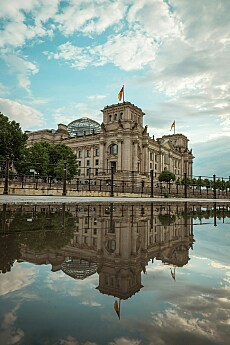 Auf dem Bild ist das Gebäude des Bundestags zu sehen. Es spiegelt sich im Wasser davor